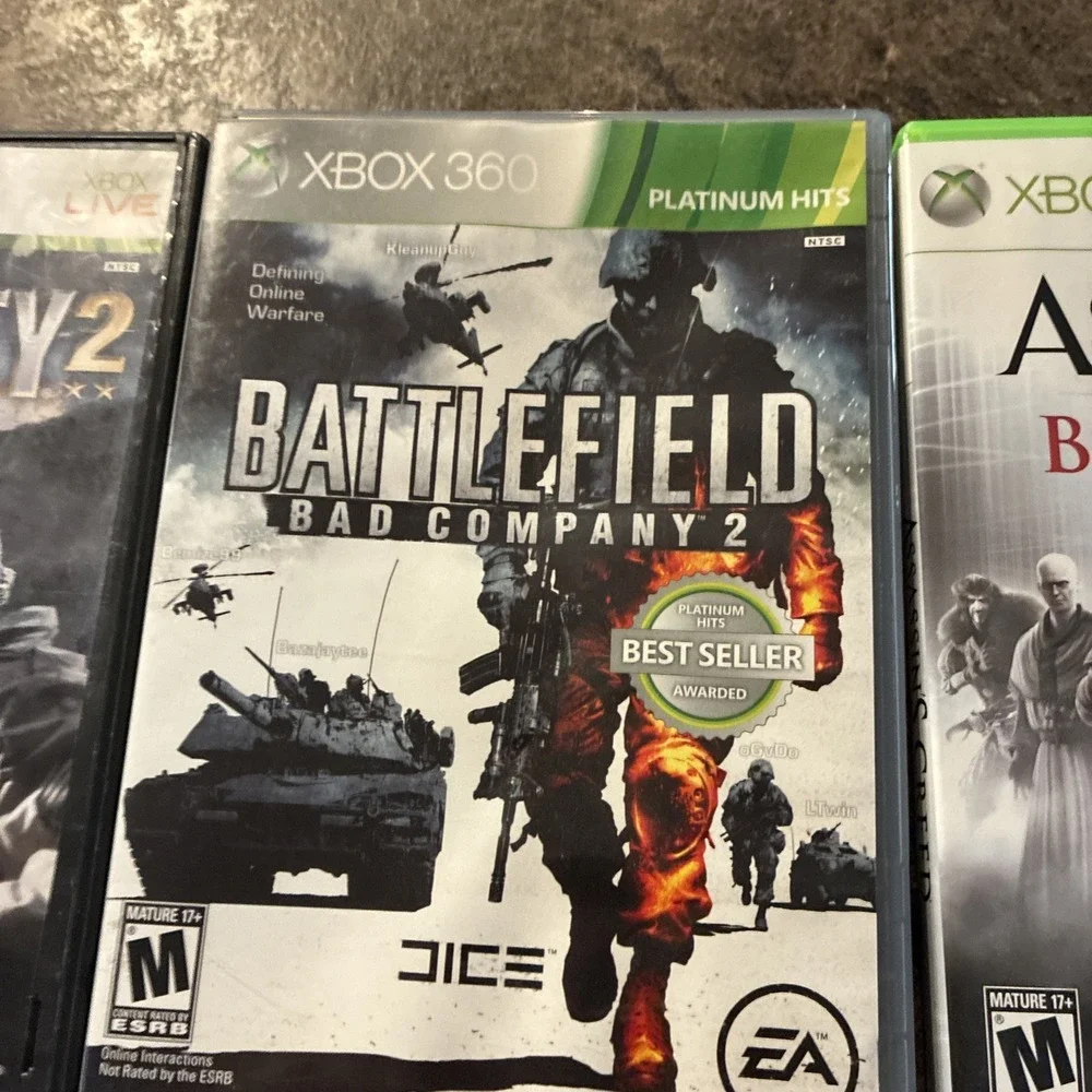 Three Xbox 360 Games, Assassin Creed, Battlefield, And Call Of Duty